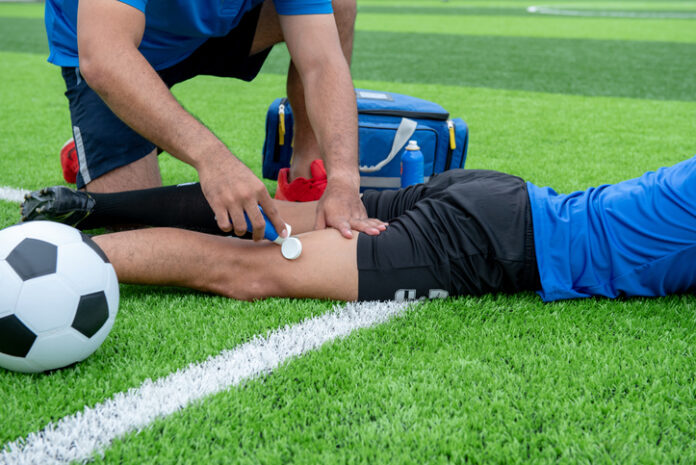 Footballer wearing a blue shirt, black pants injured in the lawn during the race.