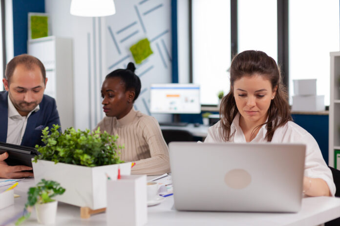 Focused woman manager typing on laptop, browsing on internet